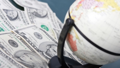 Globe resting on scattered U.S. dollar bills.