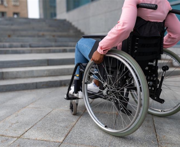 Mensch im Rollstuhl vor einer Treppe
