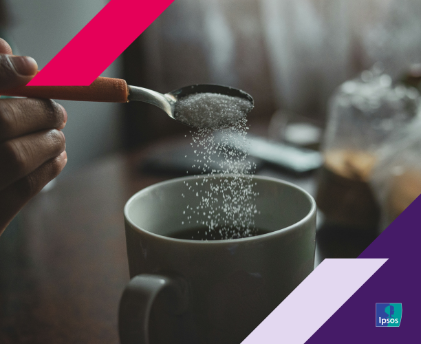 Picture of a hand pouring sweetener into a cup of coffee