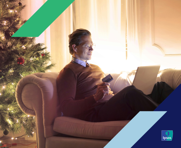 Man shopping on a laptop next to a Christmas tree